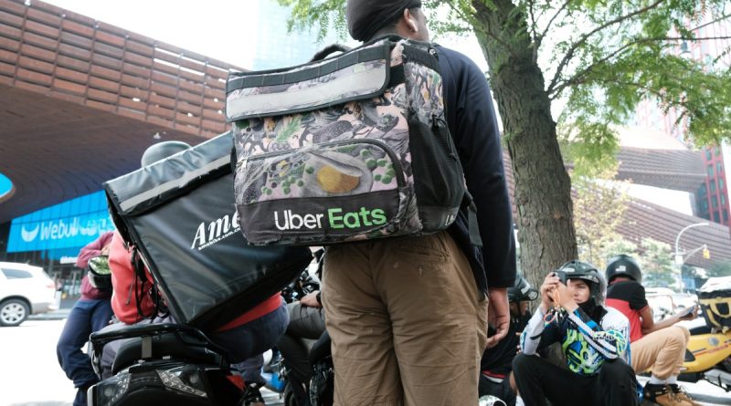 App-based delivery workers wait outside of a restaurant that uses app deliveries