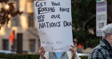 a photo of a protesters in Washington DC with a sign that says "GET YOUR FORKING HANDS OFF OUR NATION'S DATA"