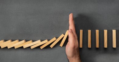 Chain Reaction In Business Concept, Businessman Intervening Dominoes Toppling; cut spending